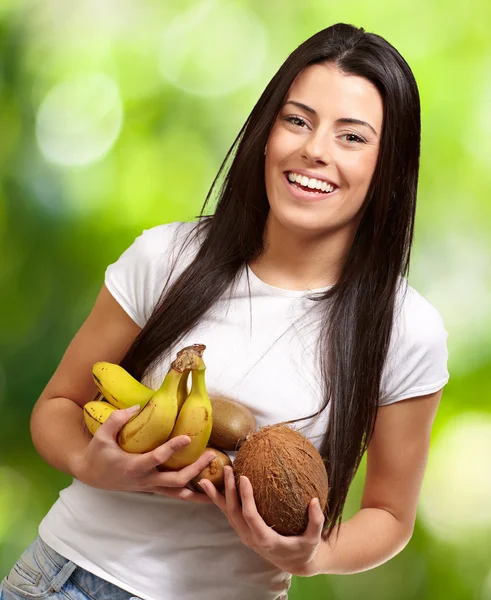 Retrato de una joven sosteniendo frutas tropicales contra una naturaleza —  Fotos de Stock