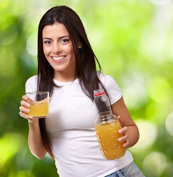 Portrait of young girl drinking orange juice against a nature ba — Stock Photo, Image