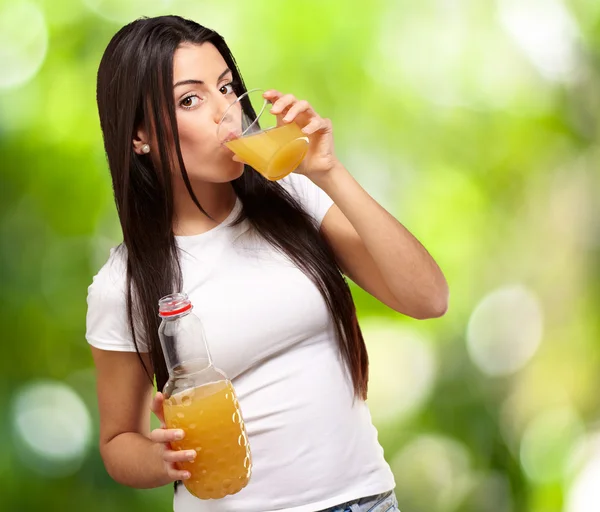 Retrato de menina bebendo suco de laranja contra uma natureza ba — Fotografia de Stock