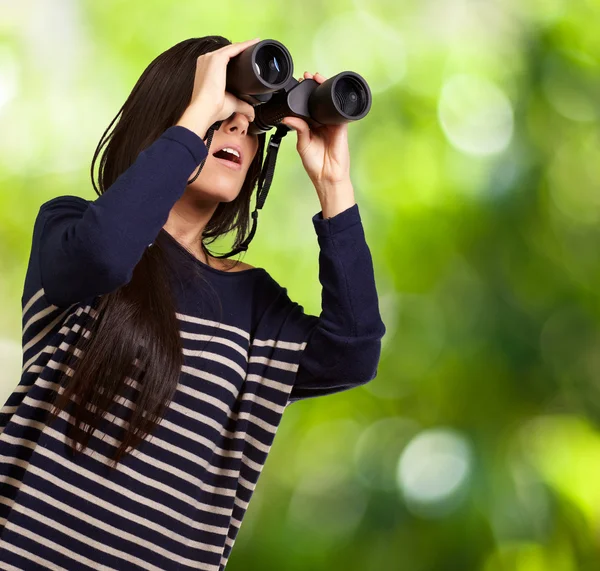 Retrato de una joven mirando a través de unos prismáticos contra una na — Foto de Stock