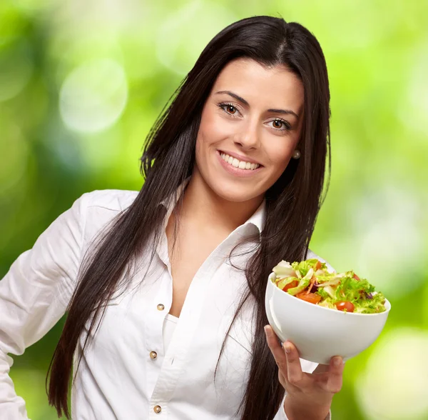 Retrato de mulher jovem que mantém a salada contra um backgroun de natureza — Fotografia de Stock