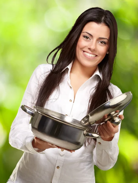 Portrait of young girl opening sauce pan against a nature backgr — Stock Photo, Image