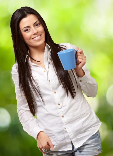 Joven chica sosteniendo taza contra un fondo de la naturaleza — Foto de Stock