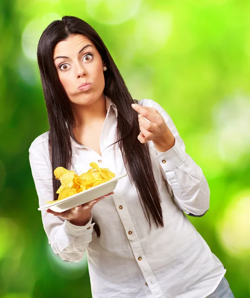 Jonge vrouw eten aardappel chips tegen een achtergrond van de natuur — Stockfoto