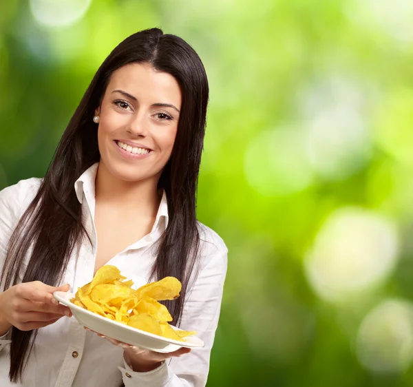 Retrato de una mujer joven sosteniendo un plato de papas fritas contra un n —  Fotos de Stock