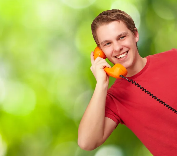 Portrait of young man talking with vintage telephone against a n Stock Photo