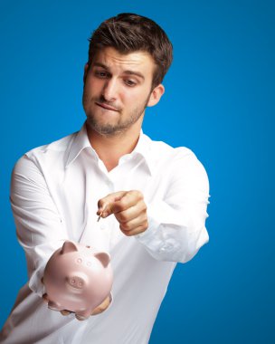 A Businessman Putting A Coin Into A Pink Piggy Bank clipart