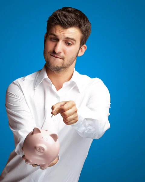 stock image A Businessman Putting A Coin Into A Pink Piggy Bank