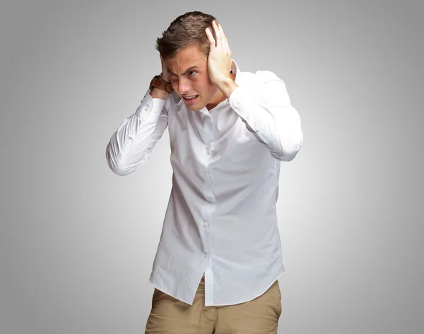 Portret van een jonge man die betrekking hebben op zijn oren met hand — Stockfoto