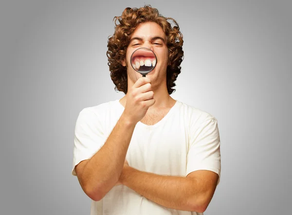 Ο άνθρωπος εξετάζει τα δόντια του με μεγεθυντικό φακό — Φωτογραφία Αρχείου
