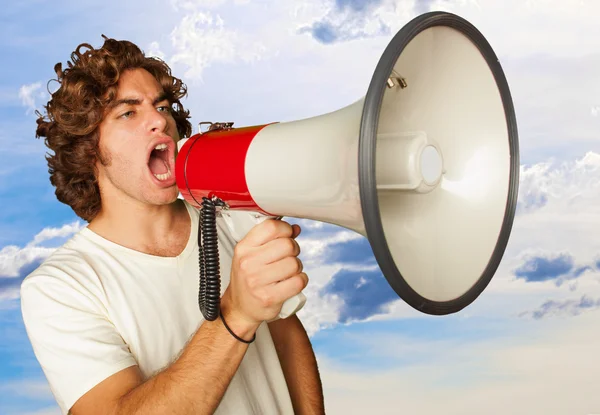 Portret van een knappe jongeman schreeuwen met megafoon — Stockfoto