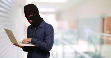 Young male thief holding laptop clipart