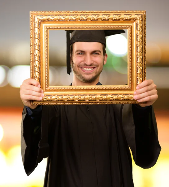Graduate man tittar genom en ram — Stockfoto
