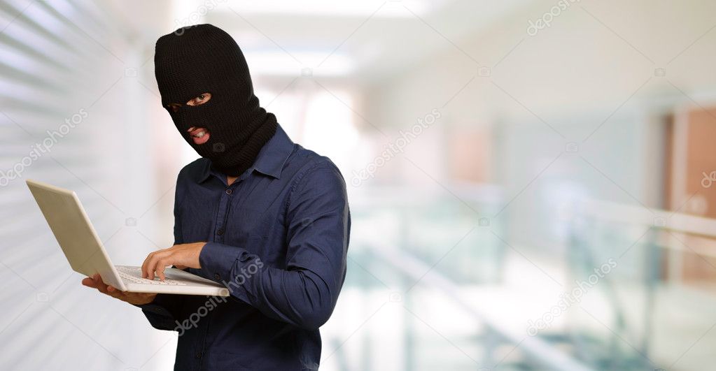 Young male thief holding laptop
