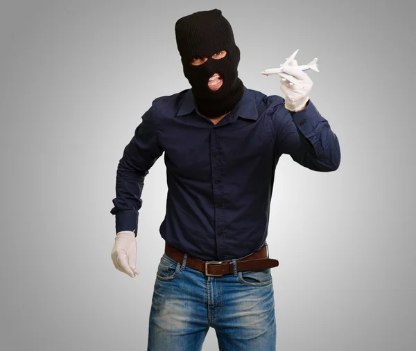 Homme portant un masque de voleur et tenant un avion miniature — Photo