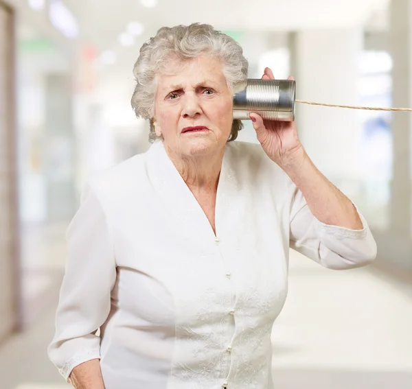 Retrato de uma mulher idosa ouvindo com estanho de metal — Fotografia de Stock