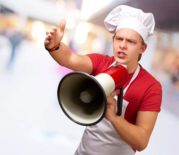 Young cook man shouting on megaphone — Stock Photo, Image