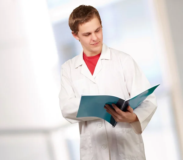 Porträt eines jungen Arztes beim Lesen einer Mappe — Stockfoto
