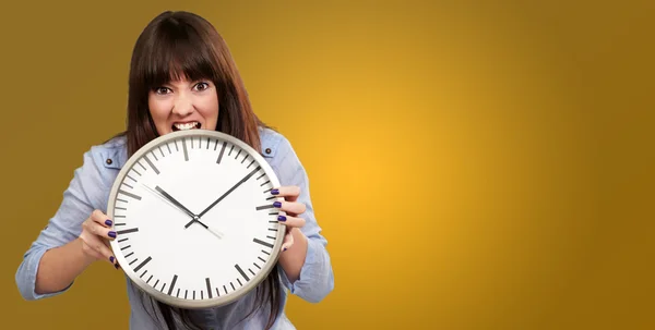 En ung flicka som håller en klocka och arg — Stockfoto