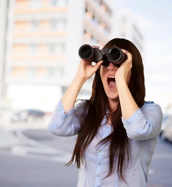 Retrato de uma jovem mulher olhando através de binóculos — Fotografia de Stock
