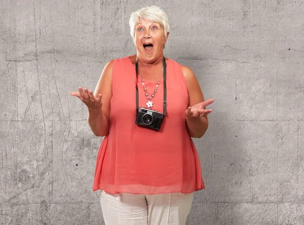 Mujer mayor usando la cámara encogiéndose de hombros — Foto de Stock