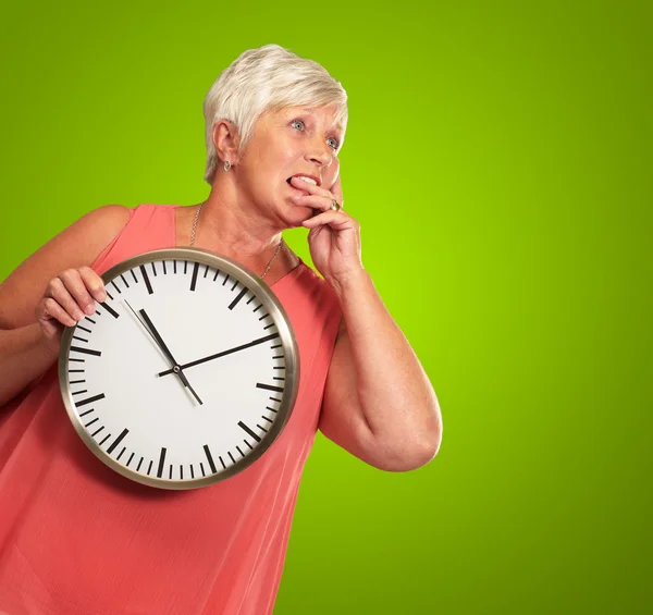 Mujer mayor sosteniendo un reloj y pensando — Foto de Stock