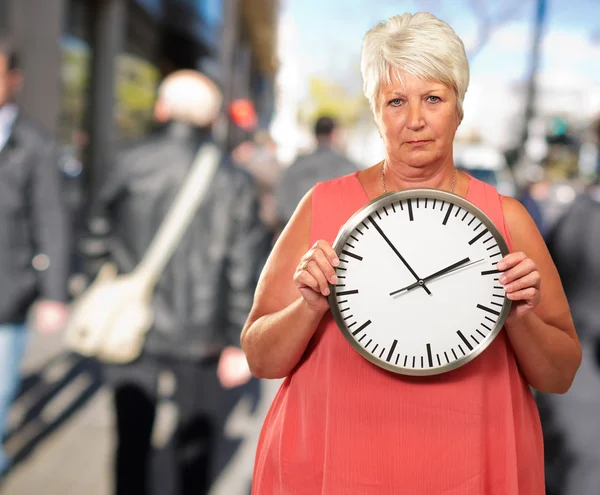 Старшая женщина держит часы — стоковое фото