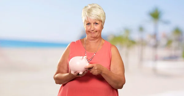 Kvinnan sätter mynt i Piggy Bank — Stockfoto