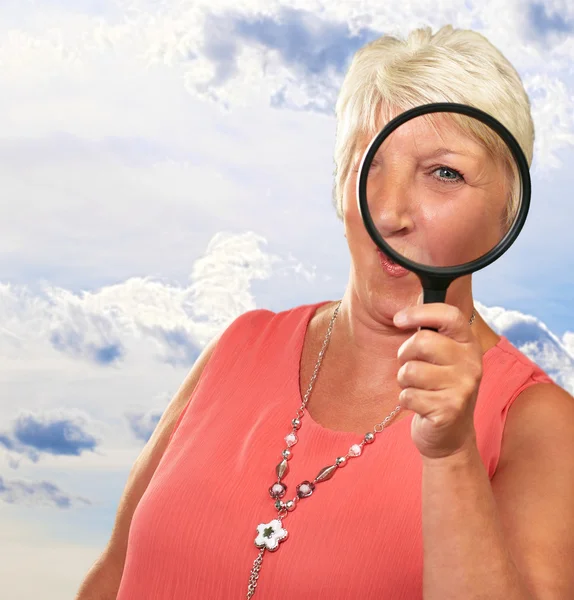 Senior vrouw kijken door een vergrootglas — Stockfoto