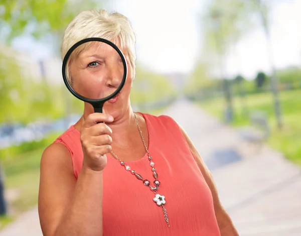 Donna anziana guardando attraverso una lente d'ingrandimento — Foto Stock