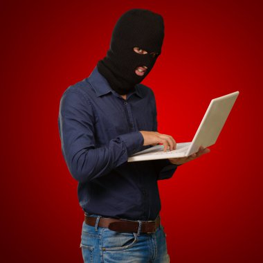 Young male thief holding laptop clipart