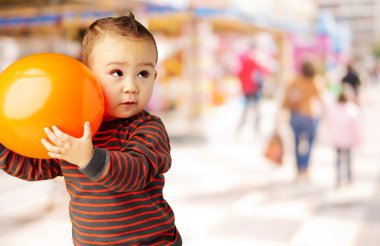 alışveriş merkezinde bir portakal balon tutan çocuk