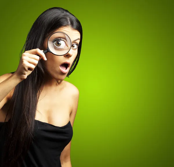 Portrait of young woman surprised looking through a magnifying g — Stock Photo, Image
