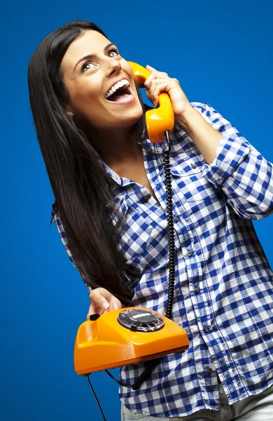 Portrait of young woman talking on vintage telephone over blue — Stock Photo, Image
