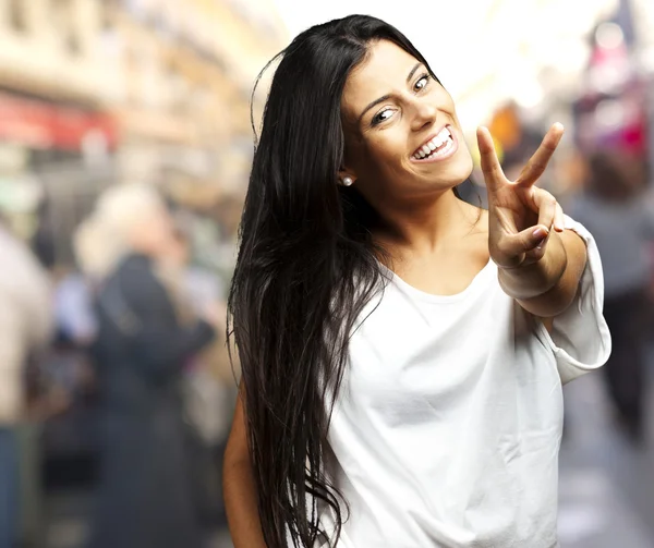 Mujer joven feliz mostrando signo de victoria —  Fotos de Stock