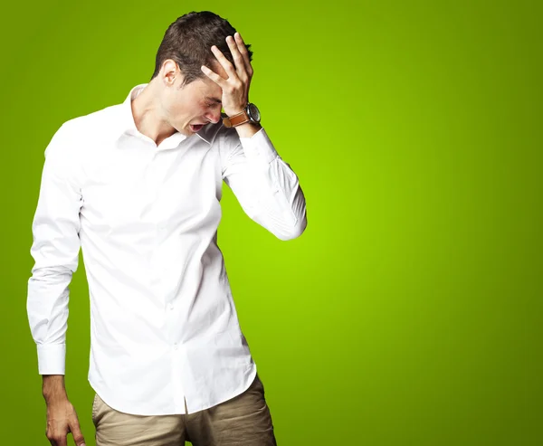 Angry young man doen frustratie gebaar op groene achtergrond — Stockfoto