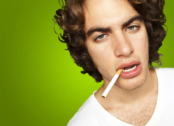 Yeşil arka plan üzerinde üzgün bir sigara içen bir portresi — Stok fotoğraf