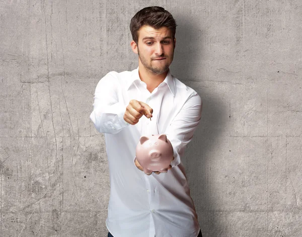 Ein Geschäftsmann steckt eine Münze in ein rosa Sparschwein — Stockfoto