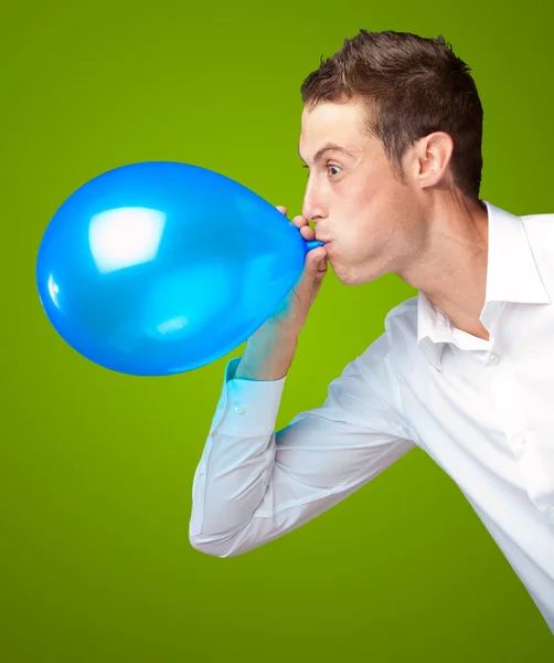 Portret van jonge man waait een ballon — Stockfoto