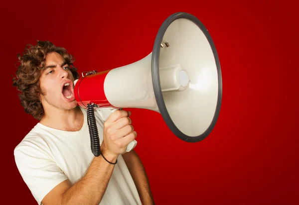 Portret van een knappe jongeman schreeuwen met megafoon — Stockfoto