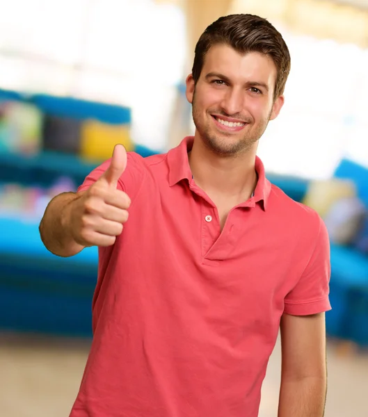 Mladý muž s úsměvem palce nahoru — Stock fotografie
