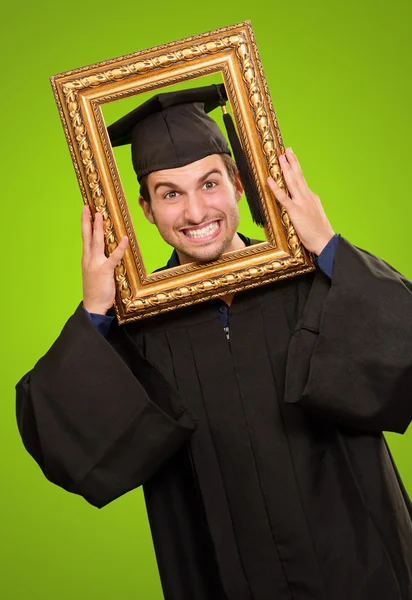 Afgestudeerde man die door een frame — Stockfoto