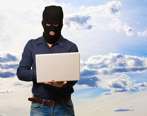 Jovem ladrão segurando laptop — Fotografia de Stock