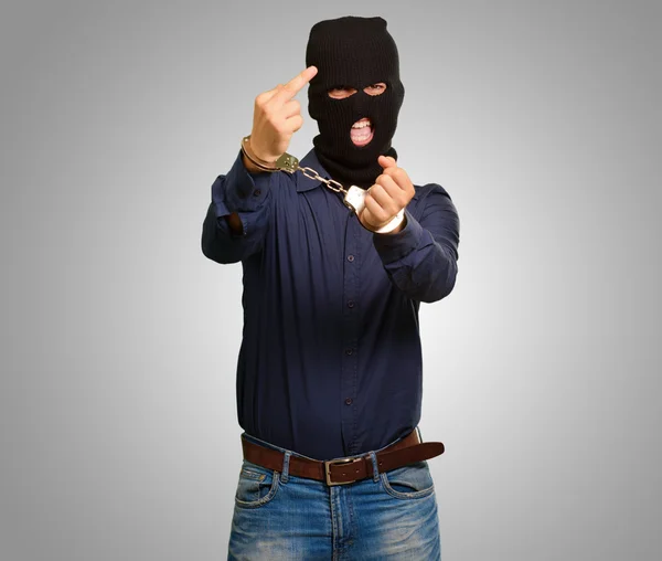 Boos criminele man vergrendeld in handboeien tegen een grijze achtergrond — Stockfoto