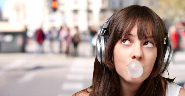 Portret van een jonge vrouw luisteren naar muziek met kauwgom weer — Stockfoto