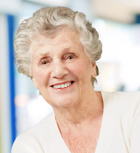 Portret van senior vrouw die lacht tegen een abstracte achtergrond — Stockfoto