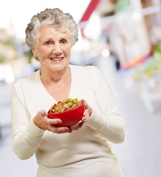 Portrait of healthy senior woman holding cereals bowl at street — Stock Photo, Image