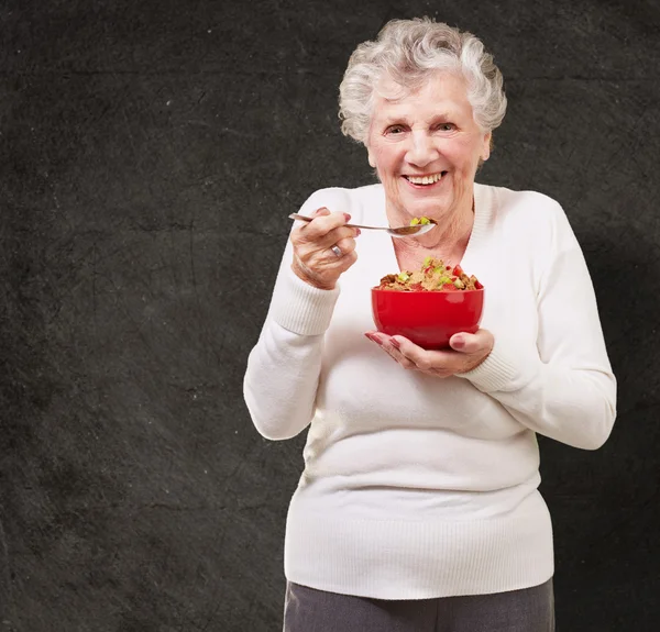 Portrait d'une femme âgée tenant un bol de céréales contre un grunge — Photo