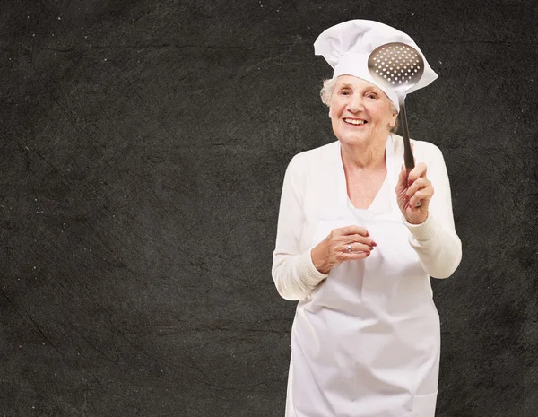 Portrait de femme cuisinière senior doux tenant une cuillère en métal à nouveau — Photo