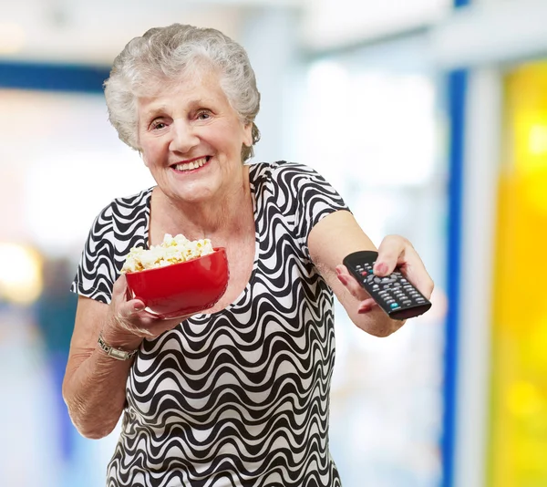 Портрет щасливої старшої жінки, яка дивиться телевізор в приміщенні — стокове фото